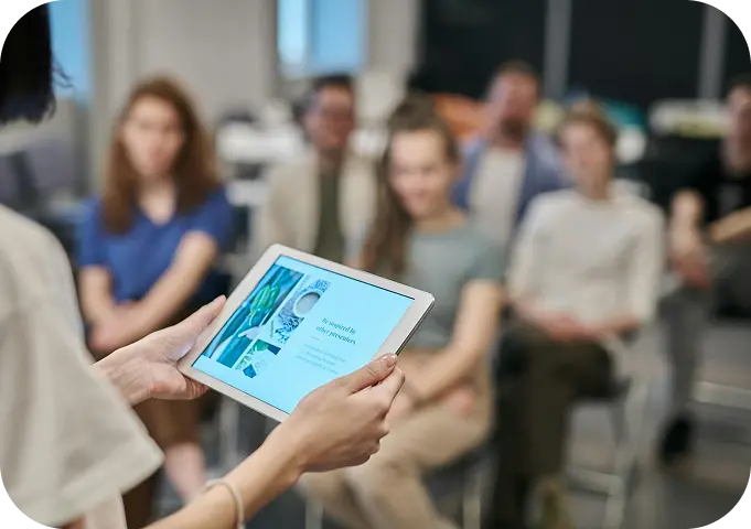 Person presenting on a tablet to a seated group